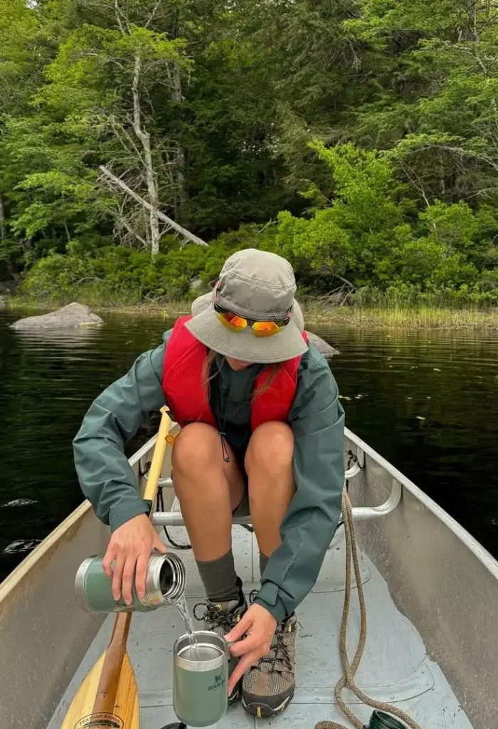The Ultimate Guide To Best Weekend Getaway Ideas For Campers 3 a camper women on the canoo on the lake while pouring coffee for weekend getaway